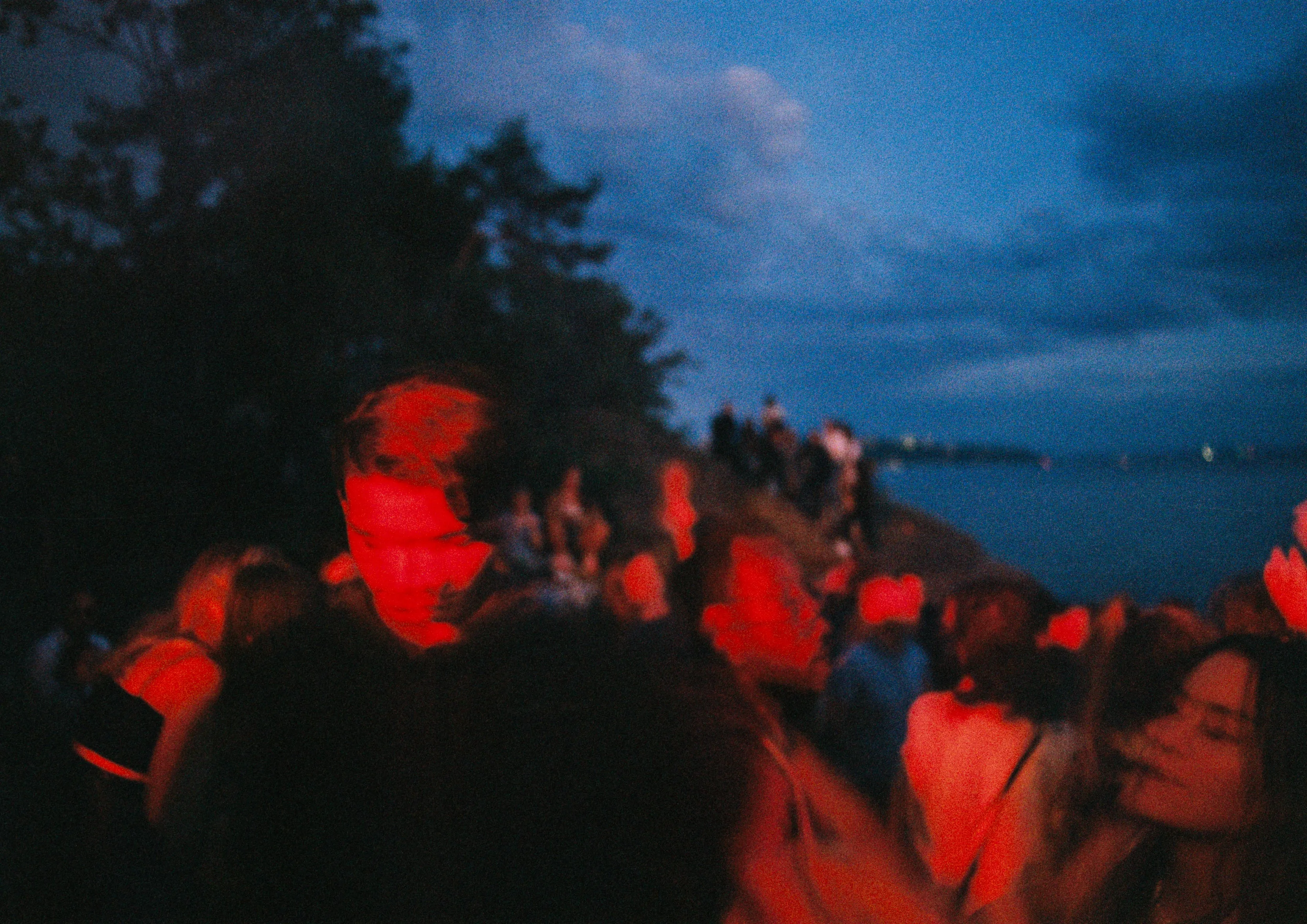 Crowd lit red at the water's edge before dawn